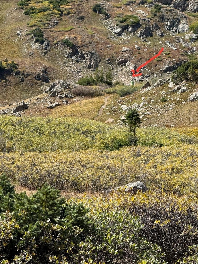 A red arrow points to a hiker tiny in the distance.
