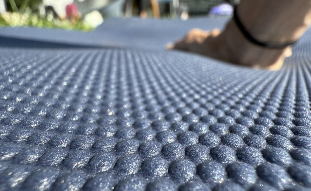A hand is shown on a closeup of a yoga mat.