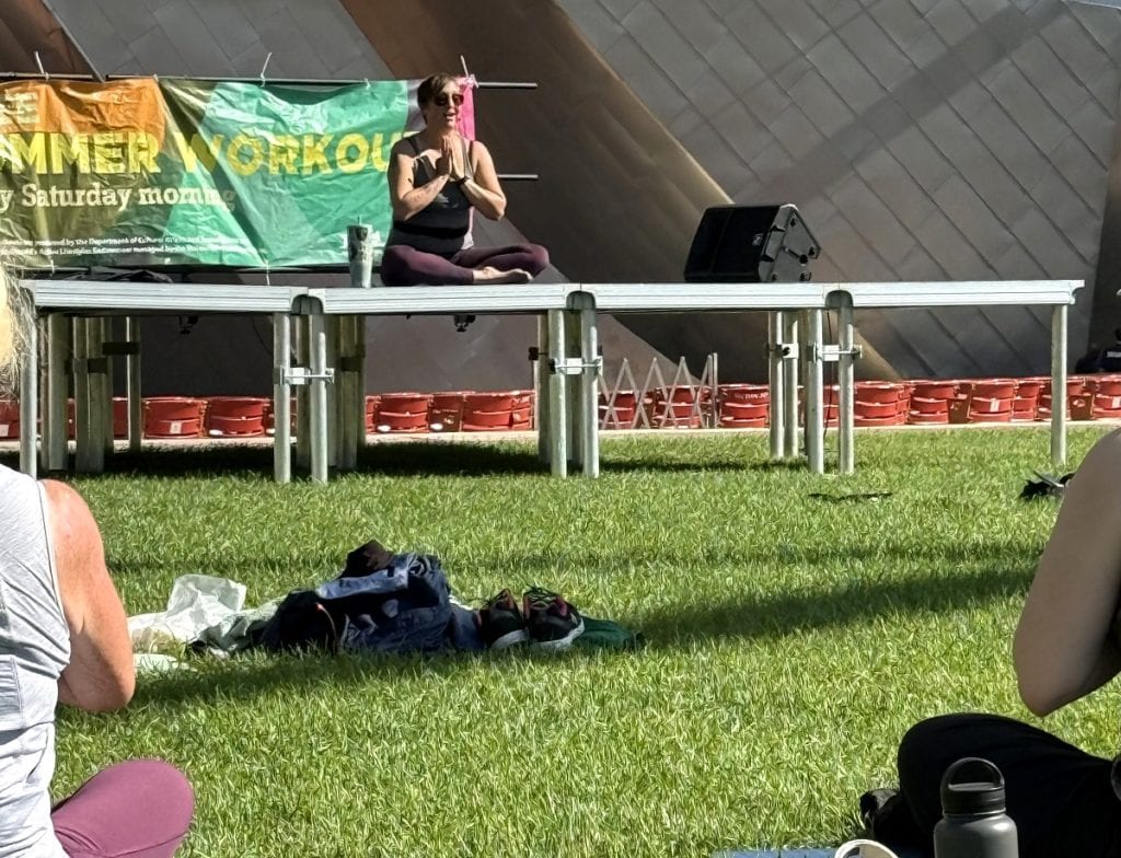 A woman sits in a yoga pose on a platform.