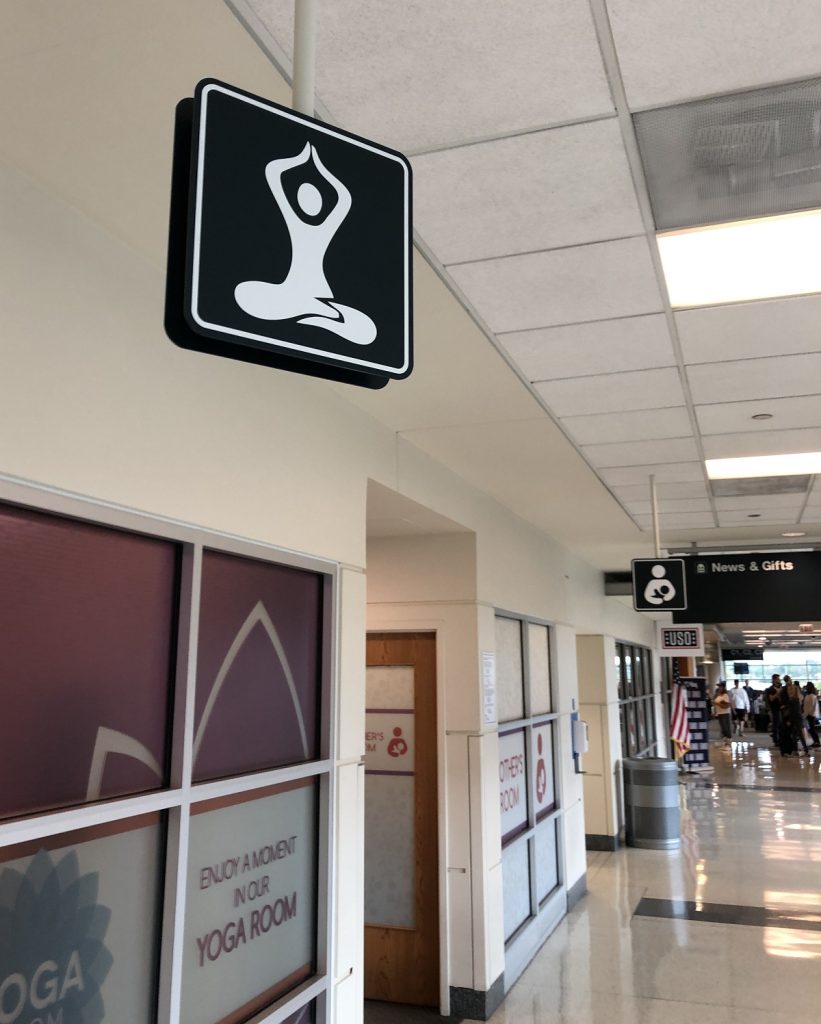 A yoga sign hangs near a room in an airport.