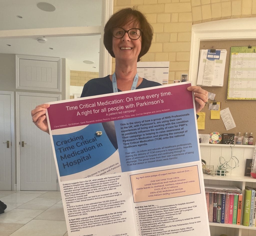 A woman in an office holds up a poster.