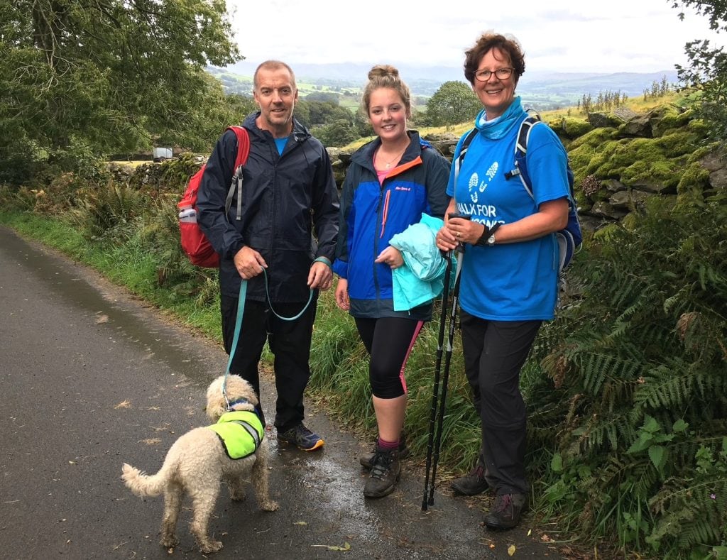 Three hikers and a dog pose for a picture.