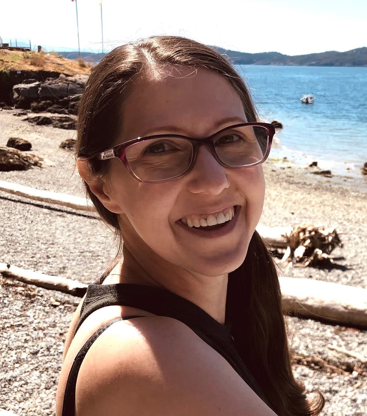 A woman smiles with the shore behind her.