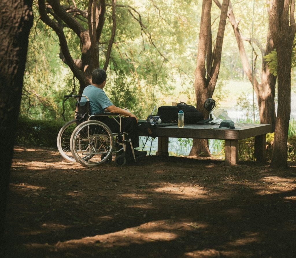 A man in a wheelchair sits at a campsite.