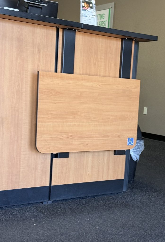 A fold-down writing desk is attached to a much higher checkout counter.