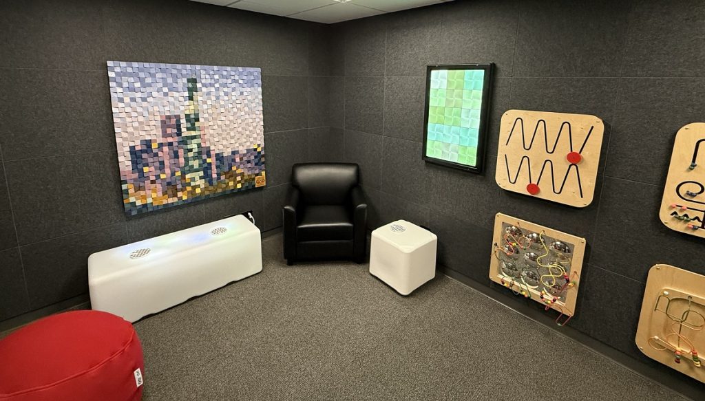 A tidy room has interesting wall hangings, comfy chairs, and low lights.