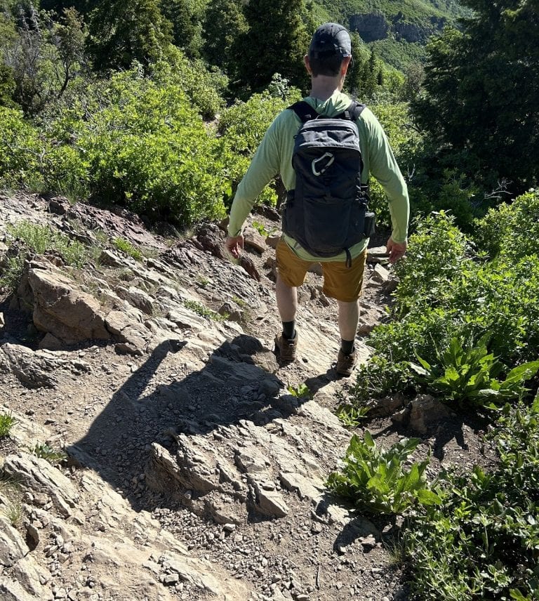 A hiker climbs down over rocks.