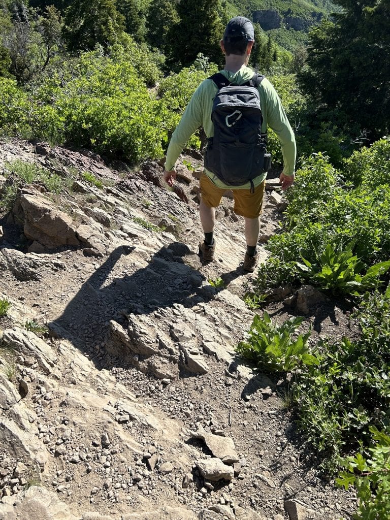A man makes his way down a rocky trail with a backpack.