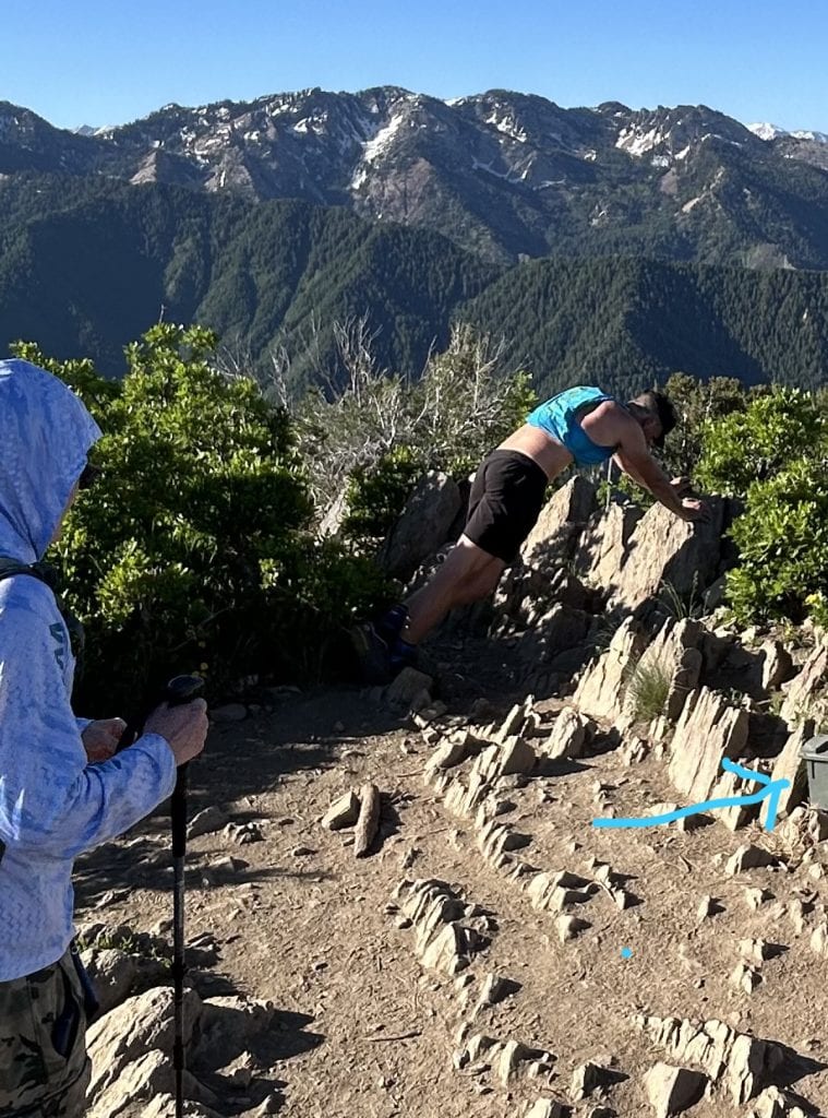 A man stretches out his legs on a summit.