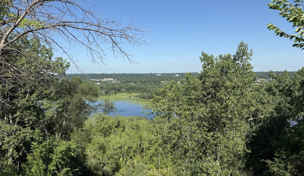 A view of a river below shows trees and sky.