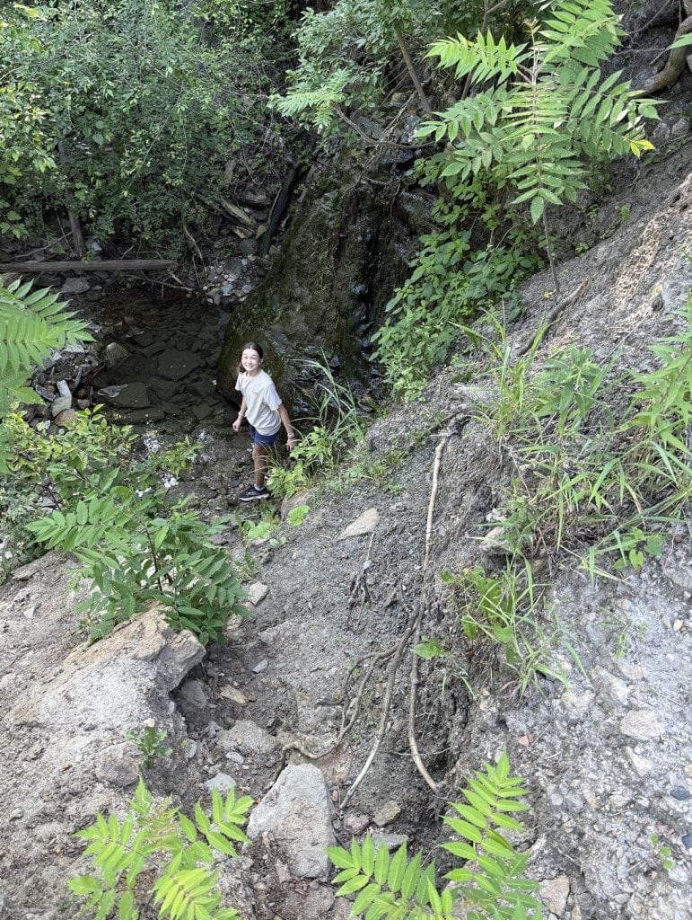 A young girl prepares to climb up a dirt hill.