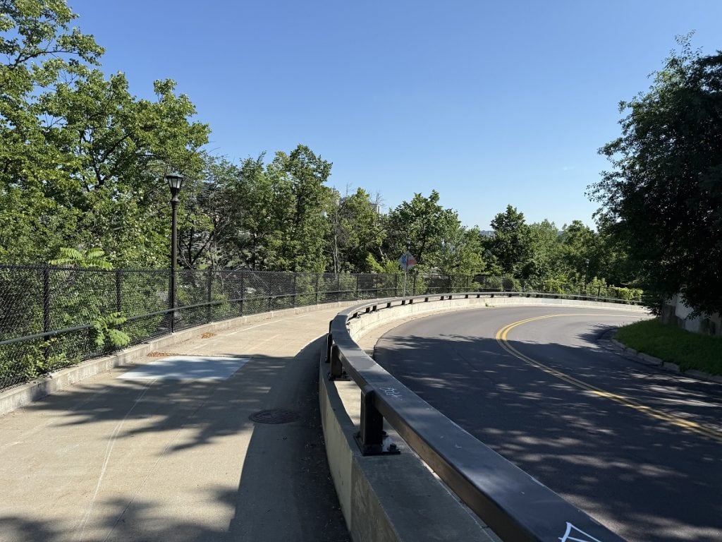 A road curves along with a sidewalk next to it.