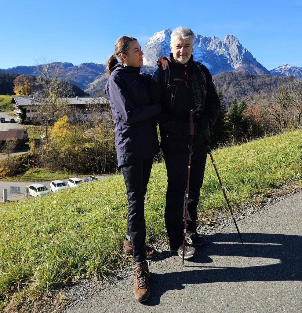 A couple stands with a Swiss mountain behind therm.