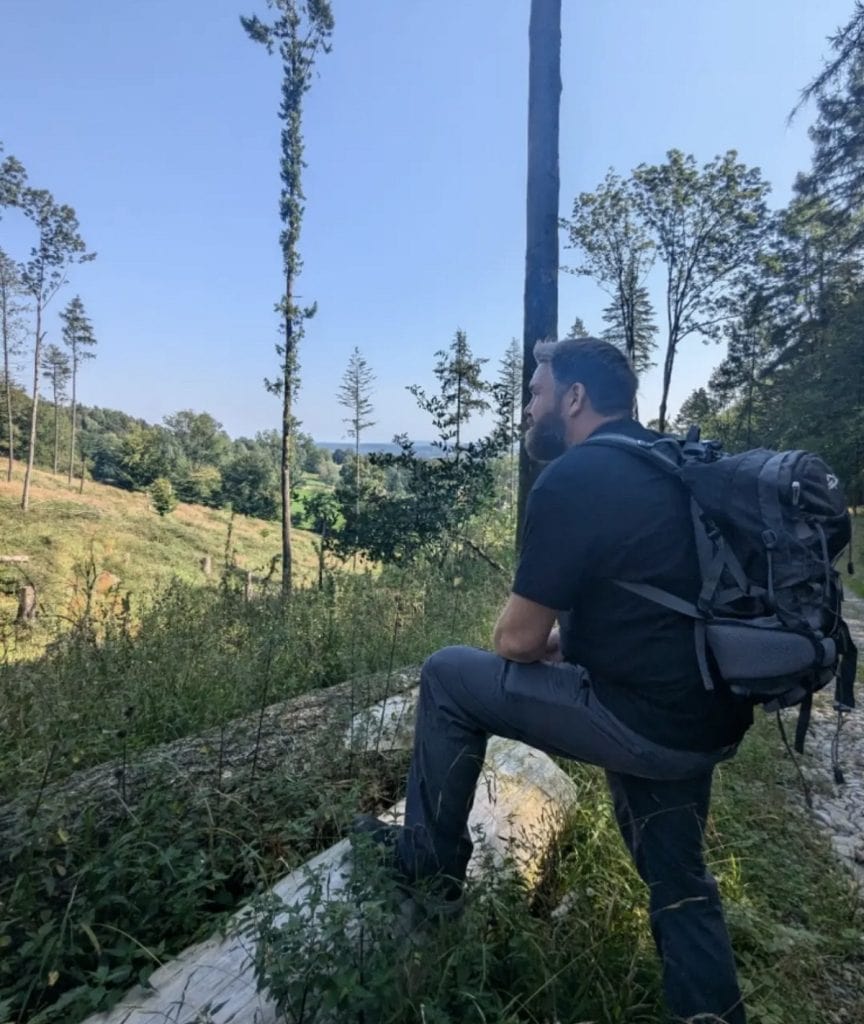 A man sits on a rock with a backpack on.