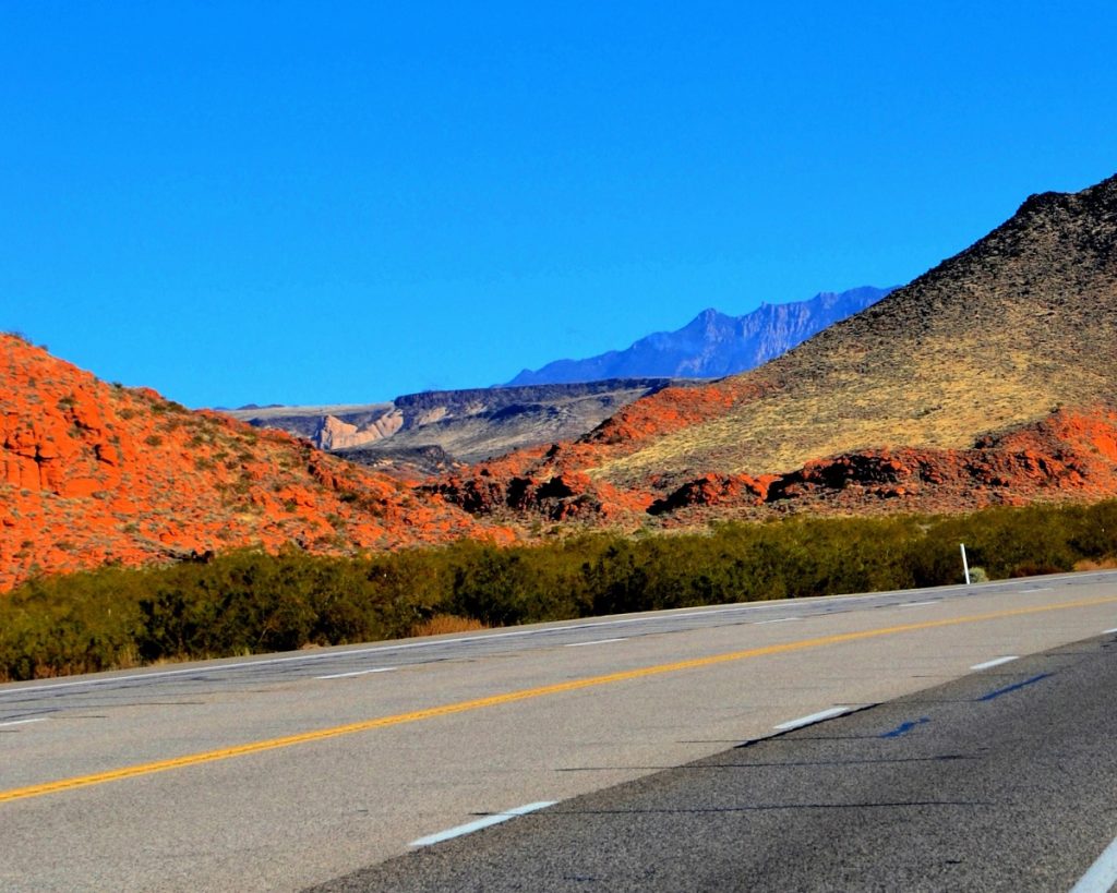 A road goes past red rocks covered by fall colors.